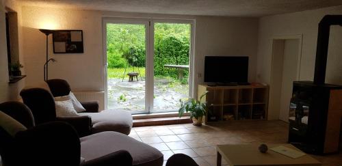 a living room with a couch and a tv and a window at Ferienhaus Neumühle in Lutzerath