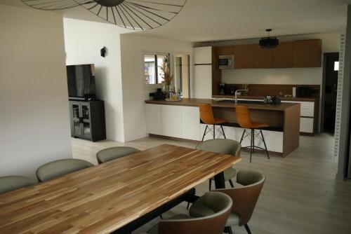 une cuisine et une salle à manger avec une table et des chaises en bois dans l'établissement Logement à 100m du virage d'Arnage- Circuit des 24h du Mans - 6 personnes, à Arnage