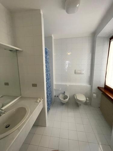 a white bathroom with a toilet and a sink at Torboletta Apartments in Nago-Torbole