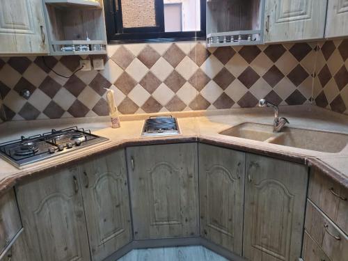 a kitchen with wooden cabinets and a stove and a sink at شقة لين طيبة للعوائل Leen Taibah Ap. for family's in Al Madinah