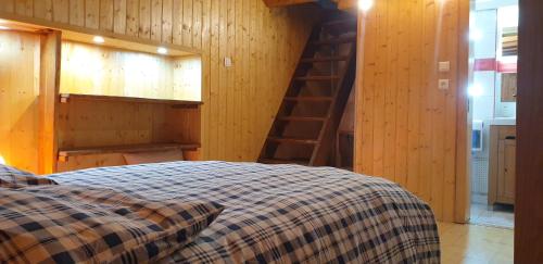 a bedroom with a bed and a wooden wall at Le chalet des nounours in Boutx