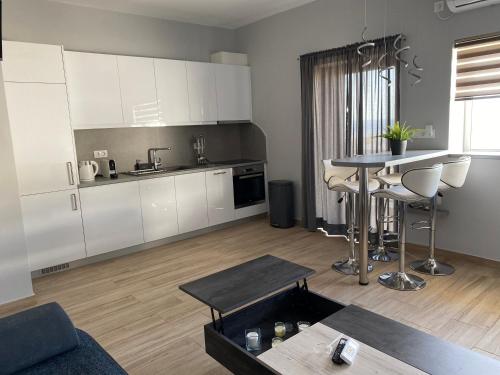 una cucina e un soggiorno con armadi bianchi e tavolo di Camelia luxury apartment a Karistos