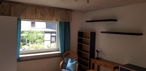 a bedroom with a window and a chair and a desk at Ferienhaus Neumühle in Lutzerath