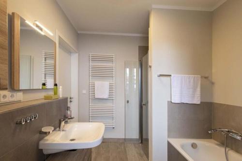 une salle de bain blanche avec un lavabo et un miroir dans l'établissement Exclusives Appartement auf Fehmarn, à Petersdorf auf Fehmarn
