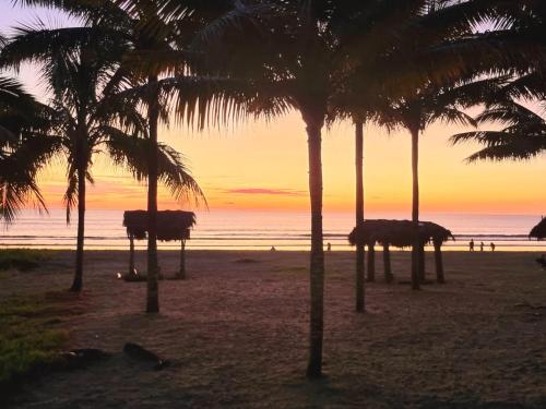 a sunset on a beach with palm trees and the ocean at CASITA MADAME in Puerto López