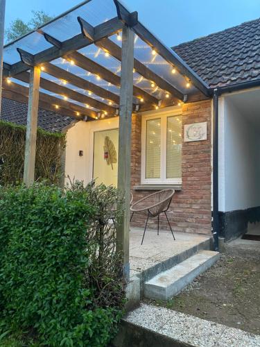 una casa con un pergolato in legno con una sedia sul portico di Le Nid du Cygne a Houlle