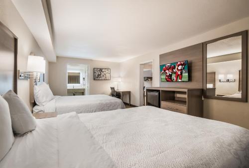 a hotel room with two beds and a mirror at Days Inn by Wyndham Chula Vista-San Diego in Chula Vista