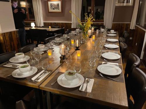 a long wooden table with plates and glasses on it at Hôtel Chalet Le Panoramique in Mizoën