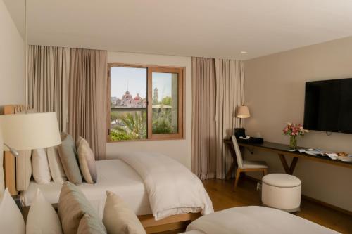 a bedroom with a bed and a desk and a window at Cartesiano Boutique & Wellness Hotel in Puebla