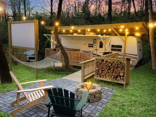 a rv with a hammock and a fire pit in a yard at Ramblin Rose Camper - Theater - Hot-Tub - Fire Pit in Jonesville