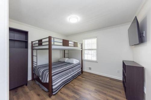 Sleeps 8, Lake Lanier Hidden Gem في بوفورد: غرفة نوم مع سرير بطابقين وتلفزيون بشاشة مسطحة