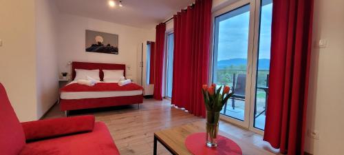 イェレニャ・グラにあるKolorowe Cieplice - Apartamenty z widokiem na Karkonoszeの赤いカーテン、ベッド1台、ソファが備わります。