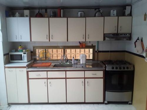 uma cozinha com armários brancos, um lavatório e um fogão em Preciosa casa de descanso a 10 min de Villa de Leyva em Sutamarchán