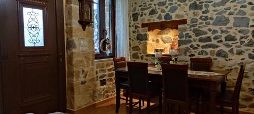 uma sala de jantar com uma mesa e uma parede de pedra em FILEMA HOME (stone house) em Anópolis