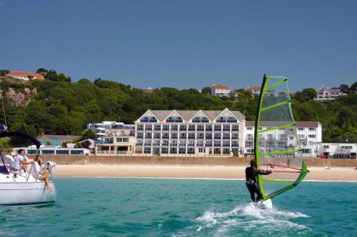 a man in the water with a sail on a boat at Golden Sands in St Brelade