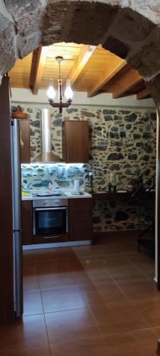 a kitchen with a stove and a stone wall at FILEMA HOME (stone house) in Anópolis