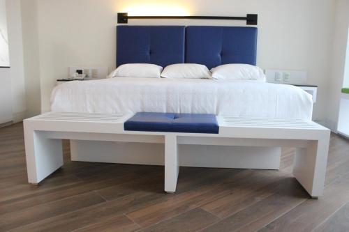 a white bed with a blue headboard and a blue bench at WeEnjoy Hotels Grand Prix Aeropuerto CDMX in Mexico City