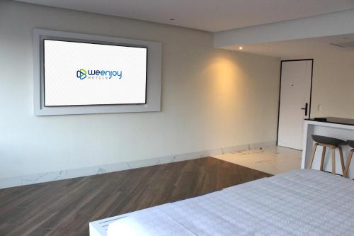 a room with a bed and a television on a wall at WeEnjoy Hotels Grand Prix Aeropuerto CDMX in Mexico City