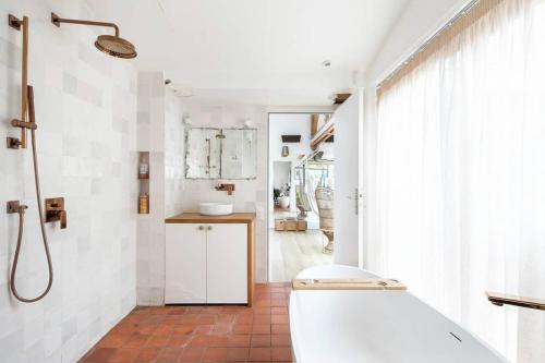 La salle de bains est pourvue d'une baignoire blanche et d'un lavabo. dans l'établissement PARIS Maison Exception Terrasse Jacuzzi Parking gratuit, à Saint-Ouen