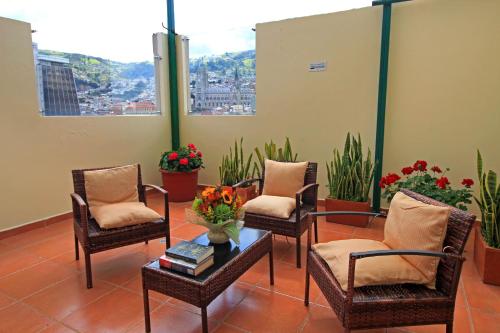a waiting room with chairs and a table and flowers at La Rosario Hotel in Quito