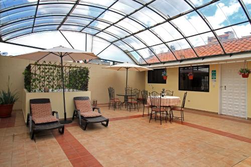 a conservatory with a table and chairs and a glass ceiling at La Rosario Hotel in Quito