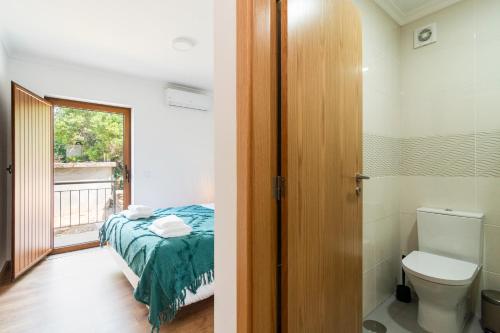 a bedroom with a bed and a bathroom with a toilet at NEW - Casa das Domingas in Vide