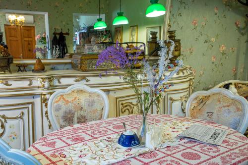 uma sala de jantar com uma mesa com um vaso de flores em Tatin - Hotel & Café in Mtskheta em Mtskheta