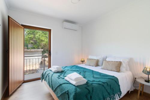 a white bedroom with a large bed and a window at Casa das Domingas in Vide