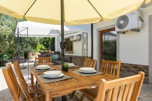 a wooden table with chairs and an umbrella at Casa das Domingas in Vide