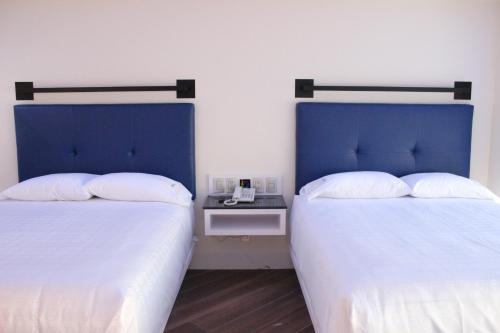 two beds sitting next to each other in a room at WeEnjoy Hotels Grand Prix Aeropuerto CDMX in Mexico City
