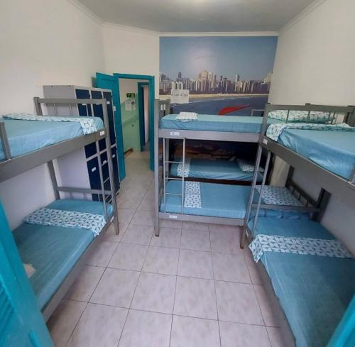 a room with three bunk beds in a room at Rolds Hostel in Santos