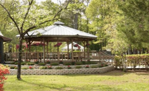 a wooden gazebo in a park with flowers at Sunburst RV Resort in Whitfield
