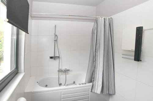 a white bathroom with a tub and a shower at marathon family villa in Schinias