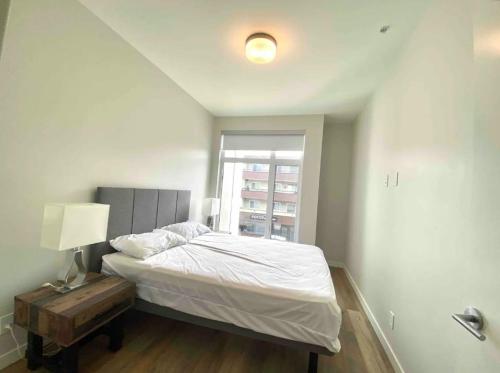 um quarto com uma cama, um candeeiro e uma janela em Brand New 3-Bedroom Condo in the Heart of Sidney em Sidney
