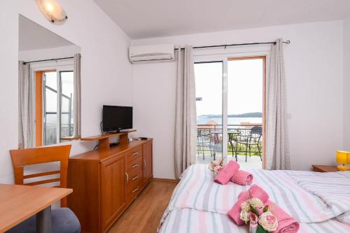 a bedroom with a bed with pink pillows and a television at Lulak Studio Apartments in Orebić