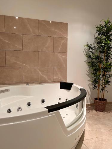 a white bath tub in a bathroom with a plant at Modern SPA - Cosy & Chic - JACCUZI in Brunoy