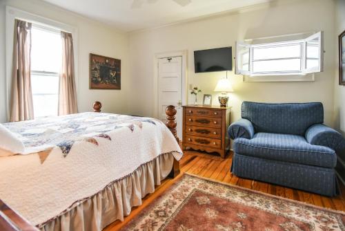 1 dormitorio con 1 cama, 1 silla y TV en Love Lane Bed & Breakfast, en Waynesville