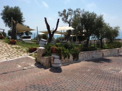 a patio with an umbrella and some plants and trees at Holiday Lodge al Porto in Mattinata