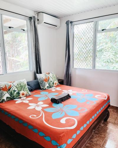 a large bed in a room with two windows at FARE ARIKI MOOREA in Afareaitu