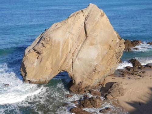 a large rock in the water on a beach at Pé na Praia in Torres Vedras