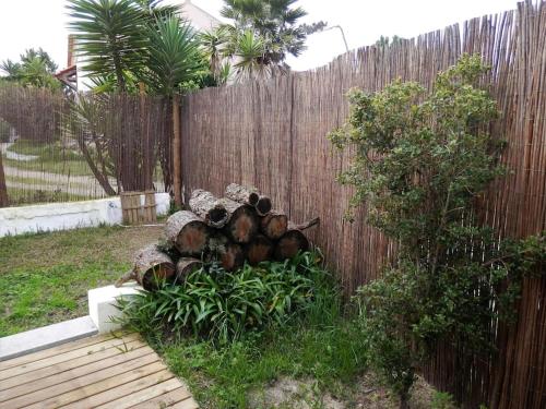 a pile of logs sitting next to a fence at Pé na Praia in Torres Vedras