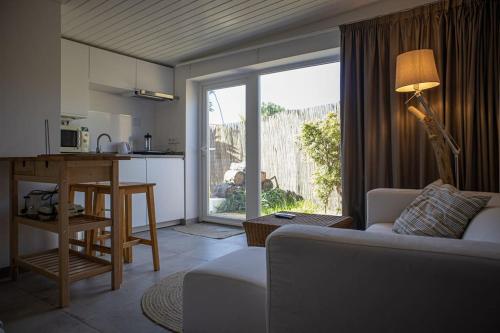 sala de estar con sofá y cocina con ventana en Pé na Praia, en Torres Vedras