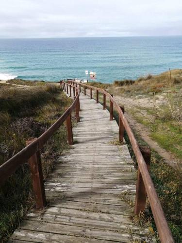 a wooden path leading to the ocean on a beach at Pé na Praia in Torres Vedras
