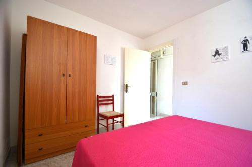 Schlafzimmer mit einem rosa Bett und einem Holzschrank in der Unterkunft Pt57 Casa vacanza per 4 pax Alba in Torre dell'Orso