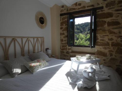 1 dormitorio con 1 cama, ventana y mesa en La Esencia Casa Rural, en Cortes de Arenoso