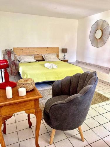 a bedroom with a bed and a chair and a table at Villa le Cotonnier Lodge in Saint-François