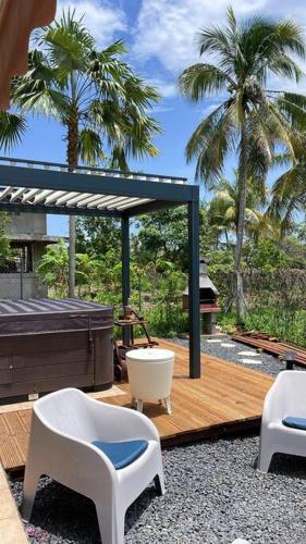 a deck with two chairs and a tub and palm trees at Villa le Cotonnier Lodge in Saint-François