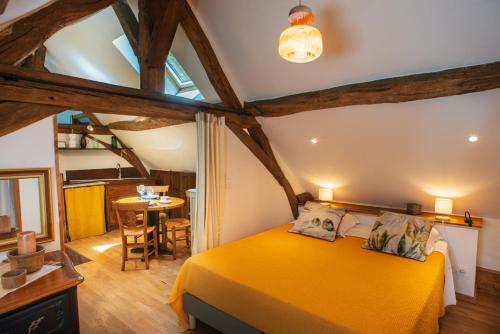 une chambre avec un lit jaune et une table dans l'établissement Maison le Village - Maison d’Hôtes, à Montagny-lès-Beaune