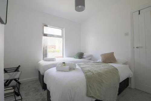 two beds in a white room with a window at StayRight 2 Bedroom House in Pontypool near Canals- Freshly renovated in Griffithstown