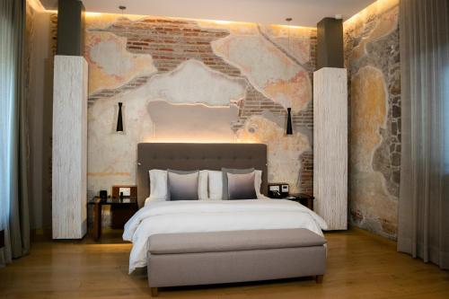 a bedroom with a large bed and a brick wall at Cartesiano Boutique & Wellness Hotel in Puebla